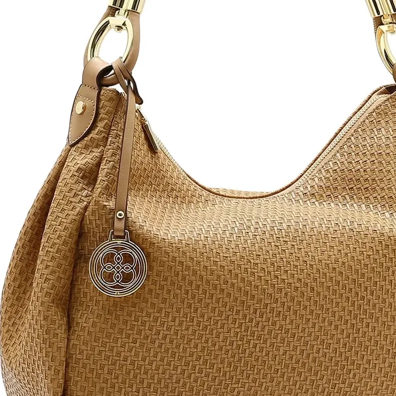 Detalhe da alça torcida dourada e pendente metálico com logo da bolsa Chenson marrom